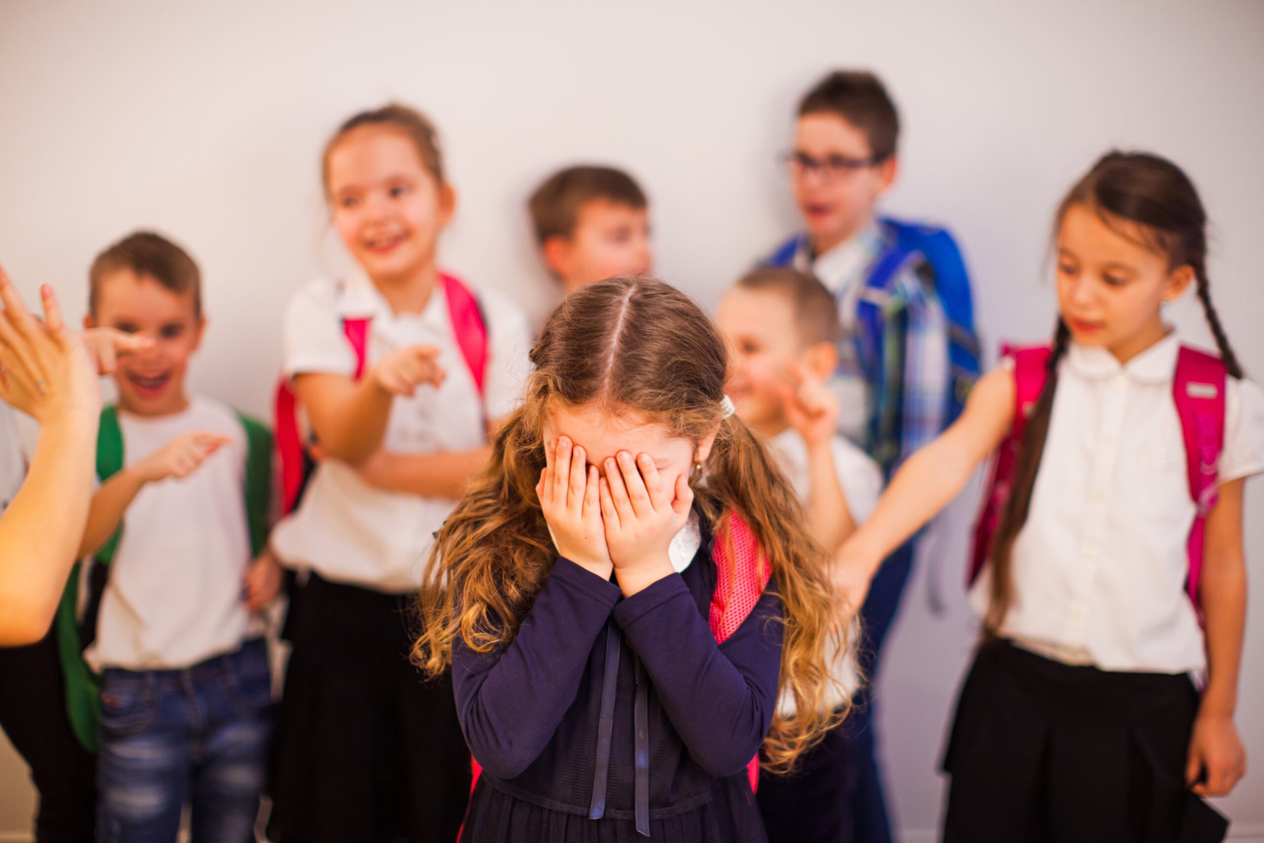 elementary-school-girl-suffers-bullying-by-classmates-sad-girl-covering-her-face-with-her-hands-stands-among-classmates-who-point-fingers-her-1